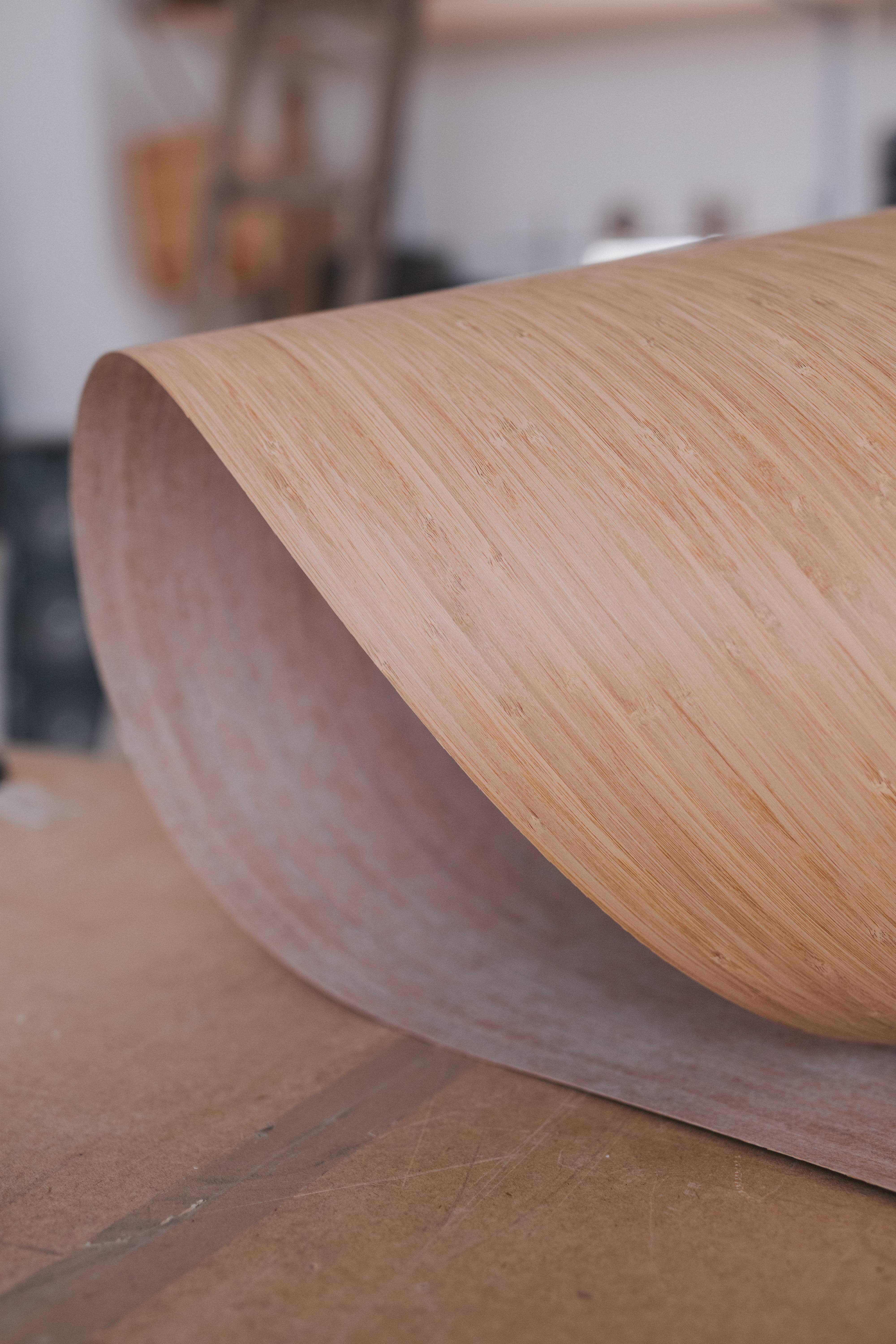 A sheet of pale wood veneer curling up from the workbench.